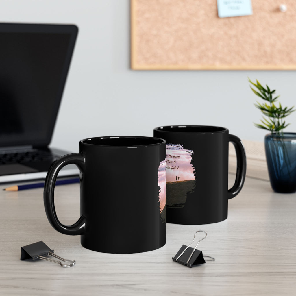 Black ceramic mug with the quote "Love is like the wind, you can't see it but you can feel it" printed on it, by Printify.